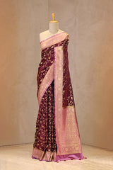 Close up of wine Semi Satin Silk Saree showing gold zari woven floral jaal on yellow body and gold zari floral patterns on contrasting border.
