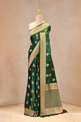 Close up of Green Semi Satin Silk Saree showing gold zari woven bird motifs with Meenakari detailing and gold zari brocade border.