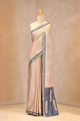 Close up of Beige Semi Tussar Silk Saree showing woven buti motifs on the body and contrasting navy blue pallu with floral designs.