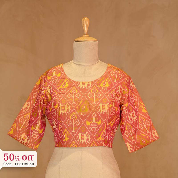 Orange ikkat print blouse on a mannequin against a brown background