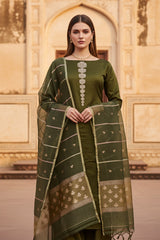 A woman in a green silk salwar suit set outfit standing in front of an architectural structure.