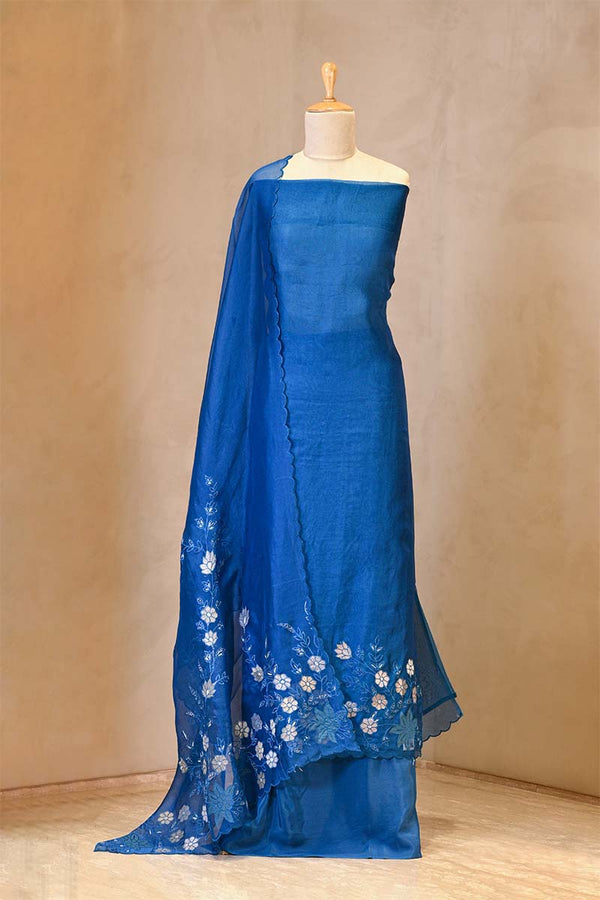 Blue saree with white floral patterns on a mannequin against a beige background