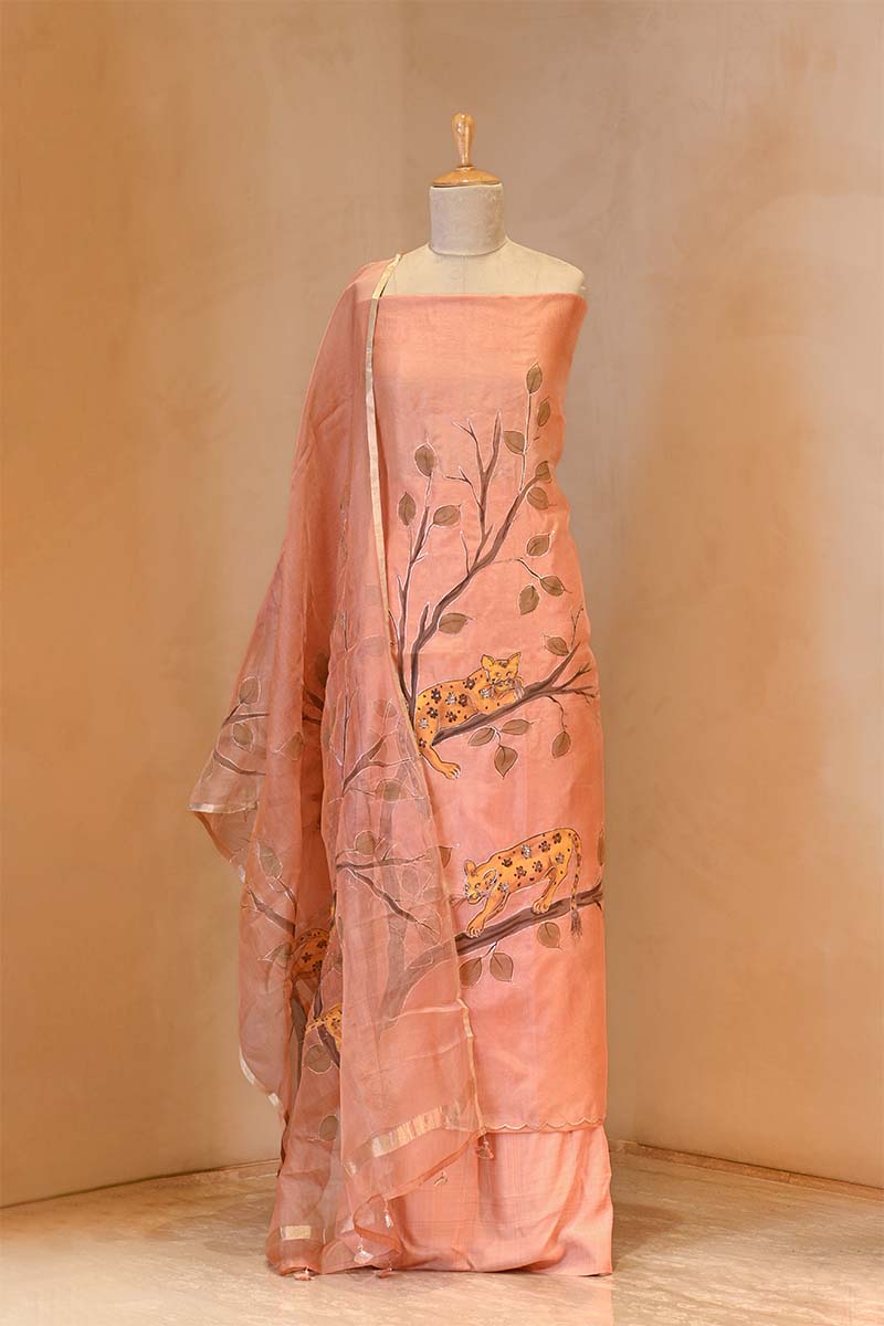 Peach-colored saree with tree and leaf design on a mannequin against a beige background