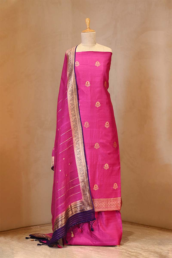 Pink saree with gold border on a mannequin against a beige background