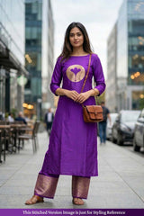 Woman in a purple outfit with a brown bag standing on a city street.