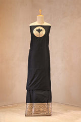 Black dress with gold embroidery on a mannequin against a beige background