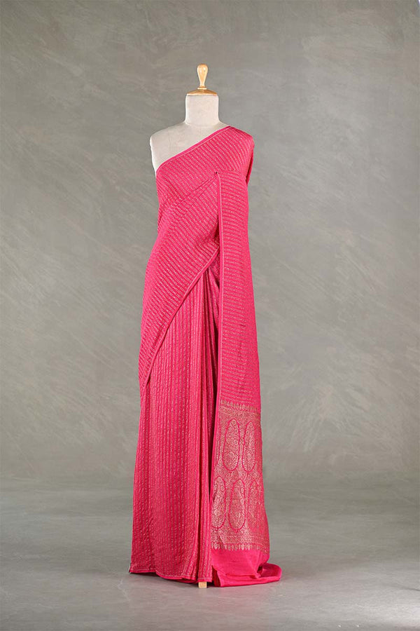Pink saree with white border on a mannequin against a gray background