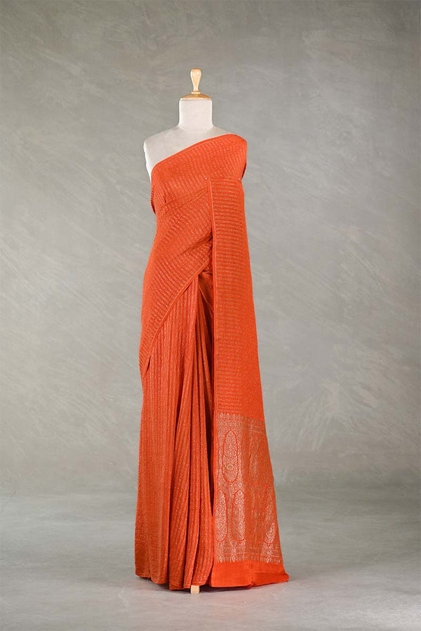 Orange saree on a mannequin against a plain background