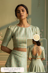 Woman wearing a light green outfit made of Banarasi Silk with a detailed blouse, standing against a neutral background.