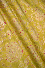 Close-up of a lime green silk fabric with gold zari woven floral pattern with red accents