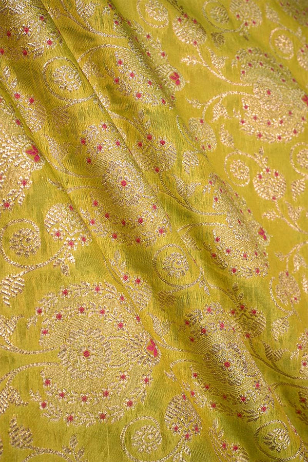 Close-up of a lime green silk fabric with gold zari woven floral pattern with red accents