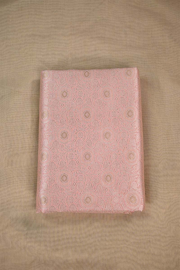 Close-up of pink fabric with intricate gold floral zari patterns on beige background