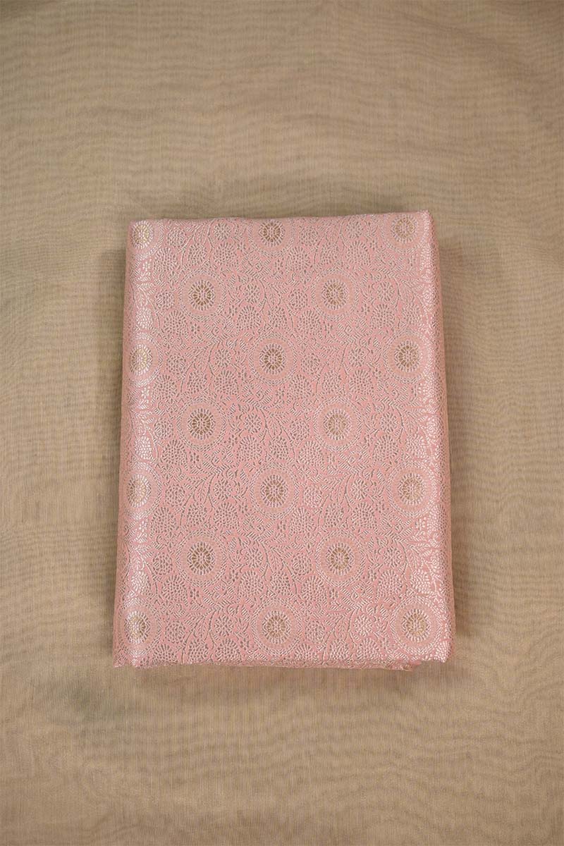 Close-up of pink fabric with intricate gold floral zari patterns on beige background