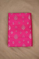 Close-up of pink raw silk fabric with gold and green floral patterns on beige background