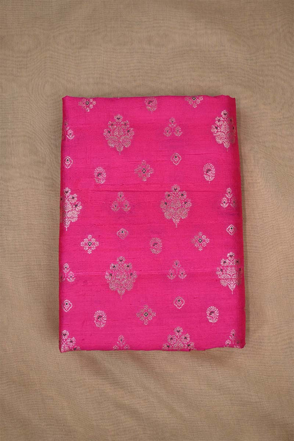 Close-up of pink raw silk fabric with gold and green floral patterns on beige background