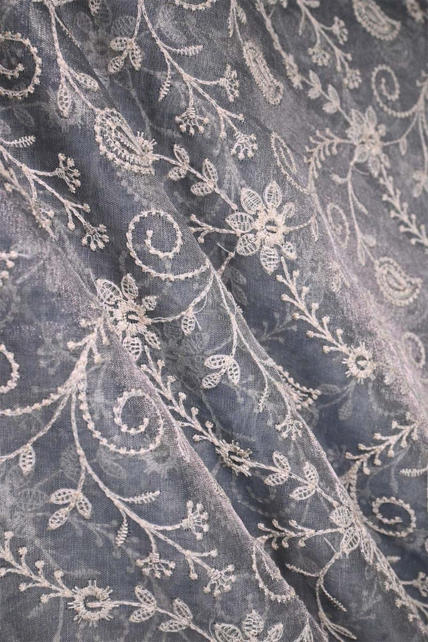 Close-up of grey embroidered fabric with floral and paisley patterns 