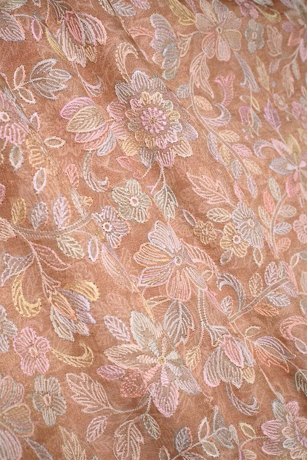 Close-up of multicolor floral pattern embroidered peach fabric 