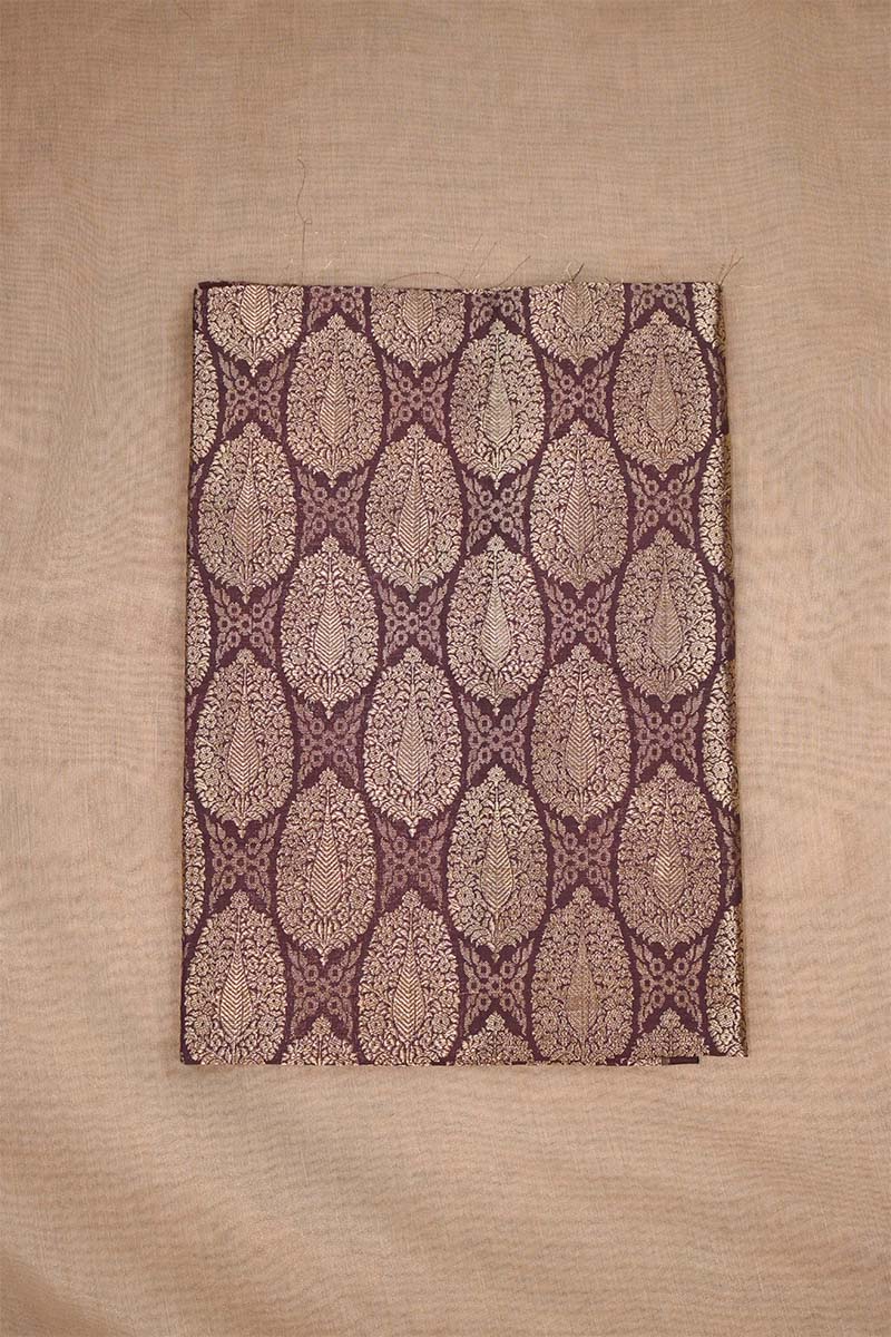 Close-up of a brown banarasi silk fabric with intricate floral brocade pattern on beige background