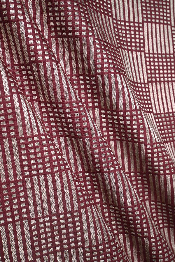 Close-up of a maroon Banarasi silk fabric with a subtle geometric pattern