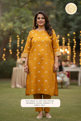 Woman wearing a mustard yellow kurta with Pichwai cow motifs patterns in an outdoor setting.