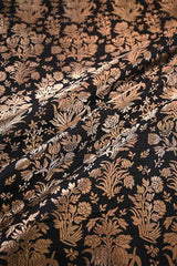 Close-up of fabric with intricate gold floral pattern on black background
