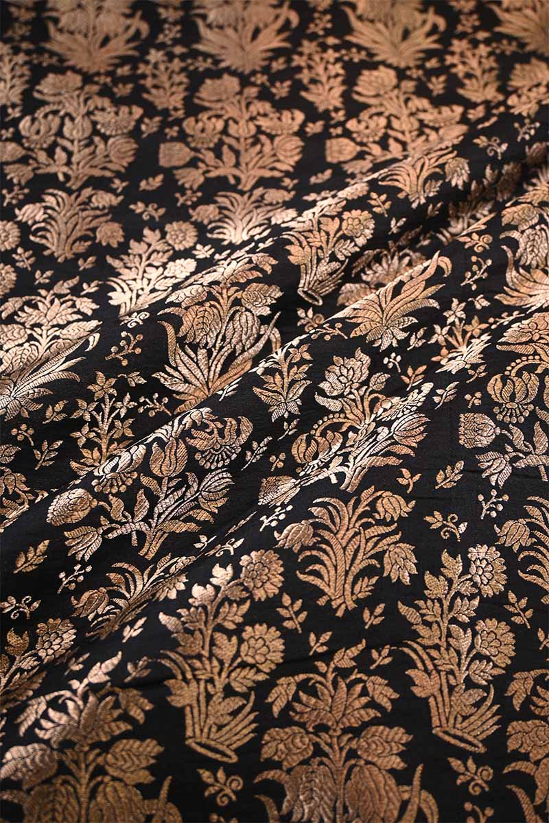 Close-up of fabric with intricate gold floral pattern on black background