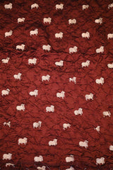 Close-up of Maroon Bandhani fabric with Pichwai motifs.