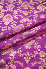 Close-up of Magenta fabric with gold zari floral motifs.