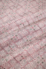 Close-up of a textured fabric with a diamond pattern in pink and gray.