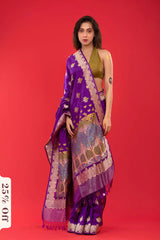 Woman wearing a purple saree with gold patterns on a red background