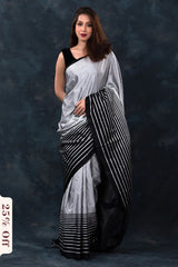 Woman wearing a black and white saree against a dark background