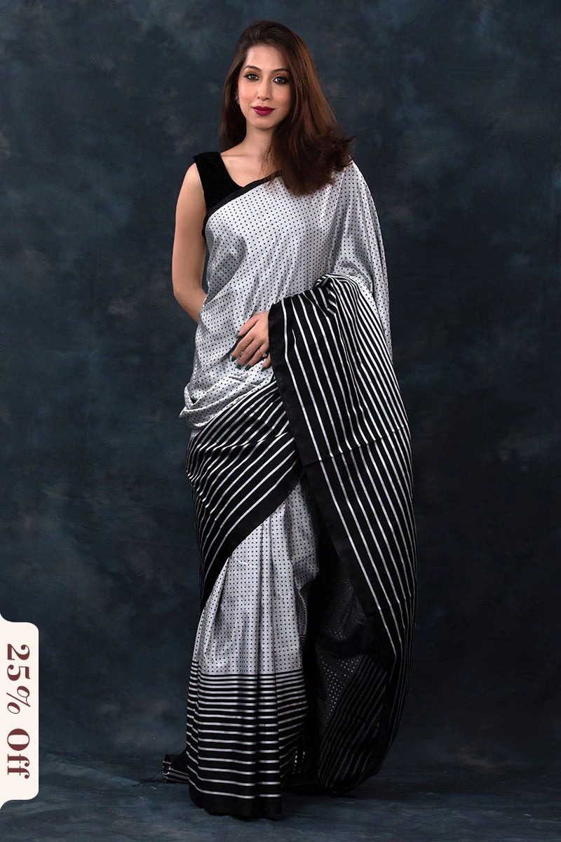 Woman wearing a black and white saree against a dark background