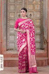 Woman wearing a pink saree with a pattern in front of an ornate door.