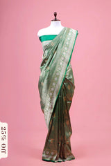 Green saree with floral patterns on a mannequin against a pink background