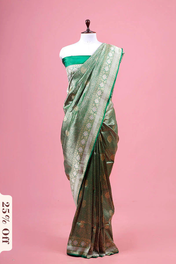 Green saree with floral patterns on a mannequin against a pink background