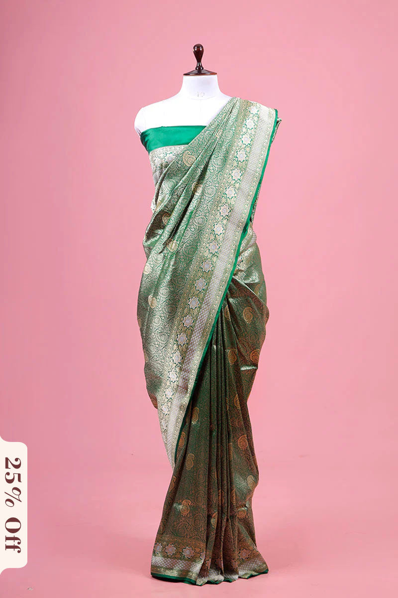 Green saree with floral patterns on a mannequin against a pink background