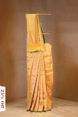 Yellow saree with green border on a wooden stand against a brown background