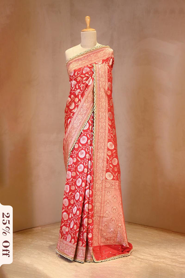 Red saree with white patterns on a mannequin against a beige background