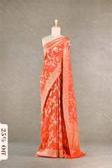 Orange saree with white patterns on a mannequin against a gray background