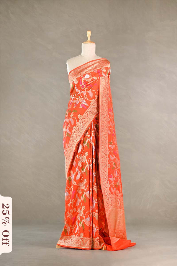 Orange saree with white patterns on a mannequin against a gray background