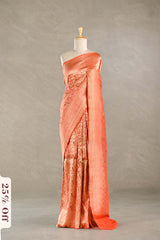Coral saree with intricate patterns on a mannequin against a neutral background