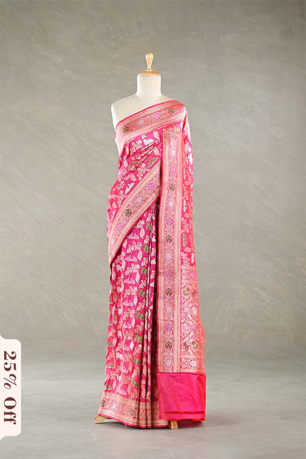 Pink Banarasi silk saree with light gold intricate Pichwai woven patterns draped on a mannequin against a gray background