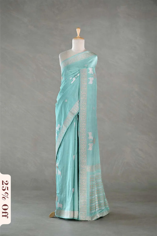 Light blue saree with white patterns on a mannequin against a gray background