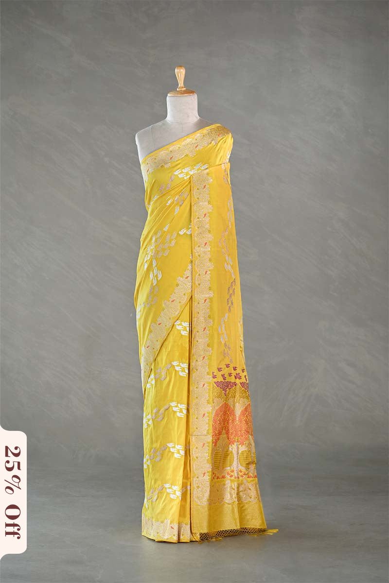 Yellow saree with floral patterns on a mannequin against a gray background