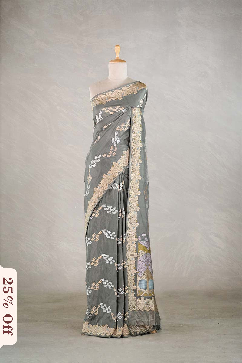 Gray saree with intricate patterns on a mannequin against a plain background