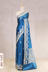 Blue saree with white embroidery on a mannequin against a plain background