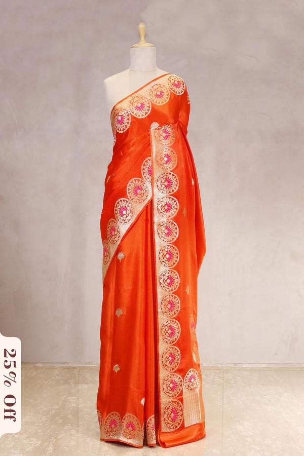 Orange saree with intricate patterns on a mannequin against a plain background
