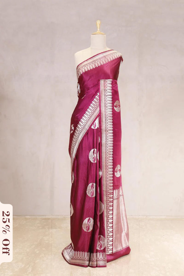 Magenta saree with white patterns on a mannequin against a light gray background