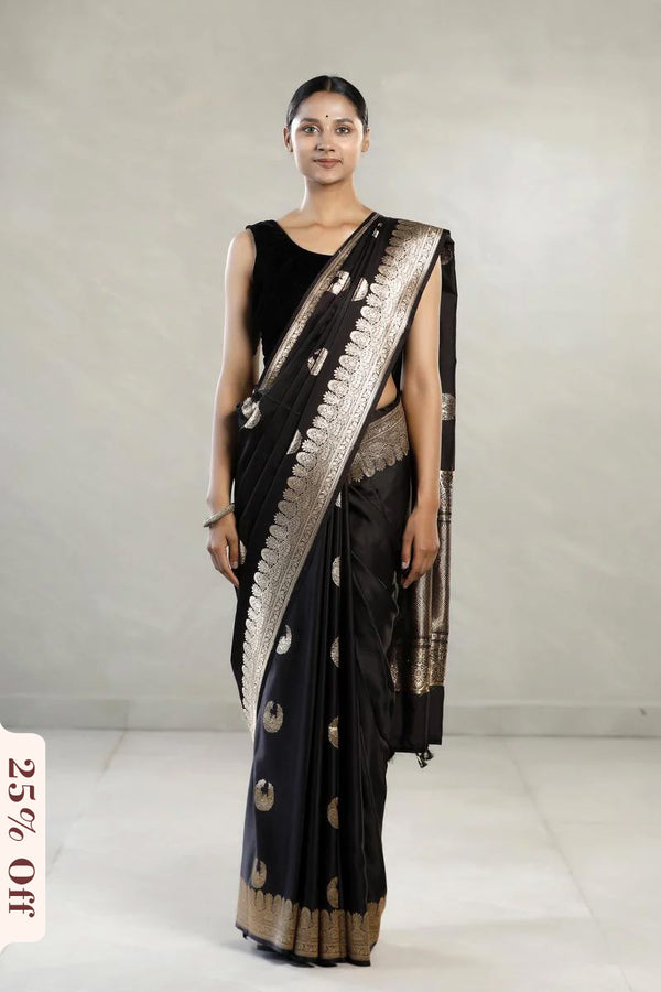 Woman wearing a black saree with gold patterns on a white background