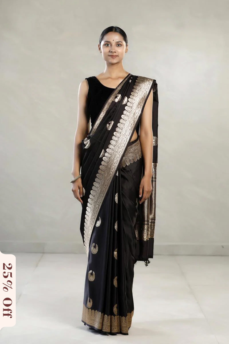 Woman wearing a black saree with gold patterns on a white background